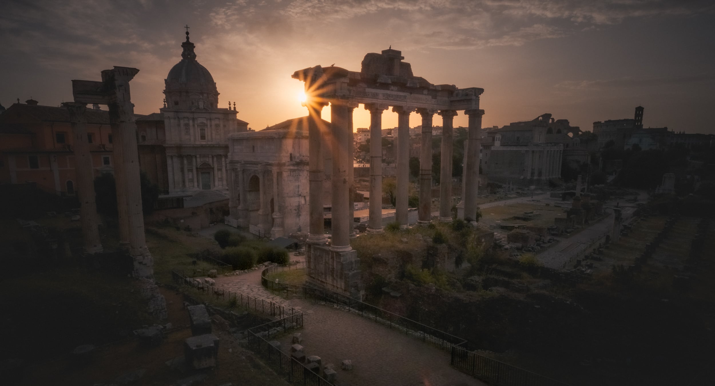 El sol asomando entre las columnas del templo de Saturno, en el Foro Romano, al amanecer.